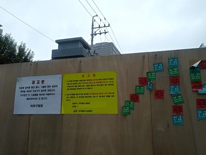 부지 바깥에 붙은 한국철도시설공단 경고장과 스티커가 서로 대비된다. 사진=김보현 기자
