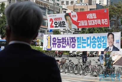 제8회 전국동시지방선거 공식 선거운동이 시작된 가운데, 한 시민이 서울 마포구 이대역 인근에 설치된 서울시장 후보자 현수막을 바라보고 있다. 사진=박정훈 기자