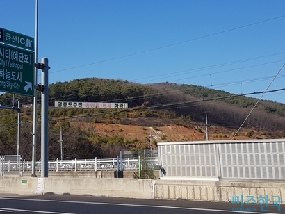 영종대교 초입 미단시티 인근 야산에 걸린 입간판. ‘영종도 주민 통행료 면제하라’고 써 있다. 사진=차형조 기자