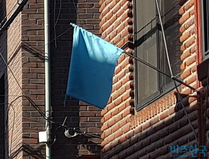 주택 외벽의 파란색 깃발은 재개발 반대를 뜻하는 표식이다. 사진=차형조 기자