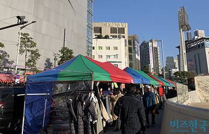 DDP 길가 한쪽에 일렬로 늘어선 임시 천막. 뒤편에 화재로 복구 중인 제일평화시장이 보인다. 사진=황채영 인턴기자