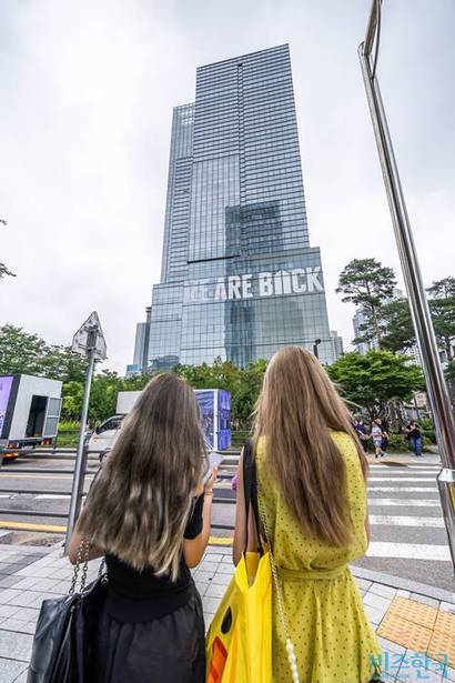 방탄소년단의 완전체 컴백을 앞두고 하이브 사옥에 걸린 홍보물을 팬들이 보고 있다. 사진=최준필 기자